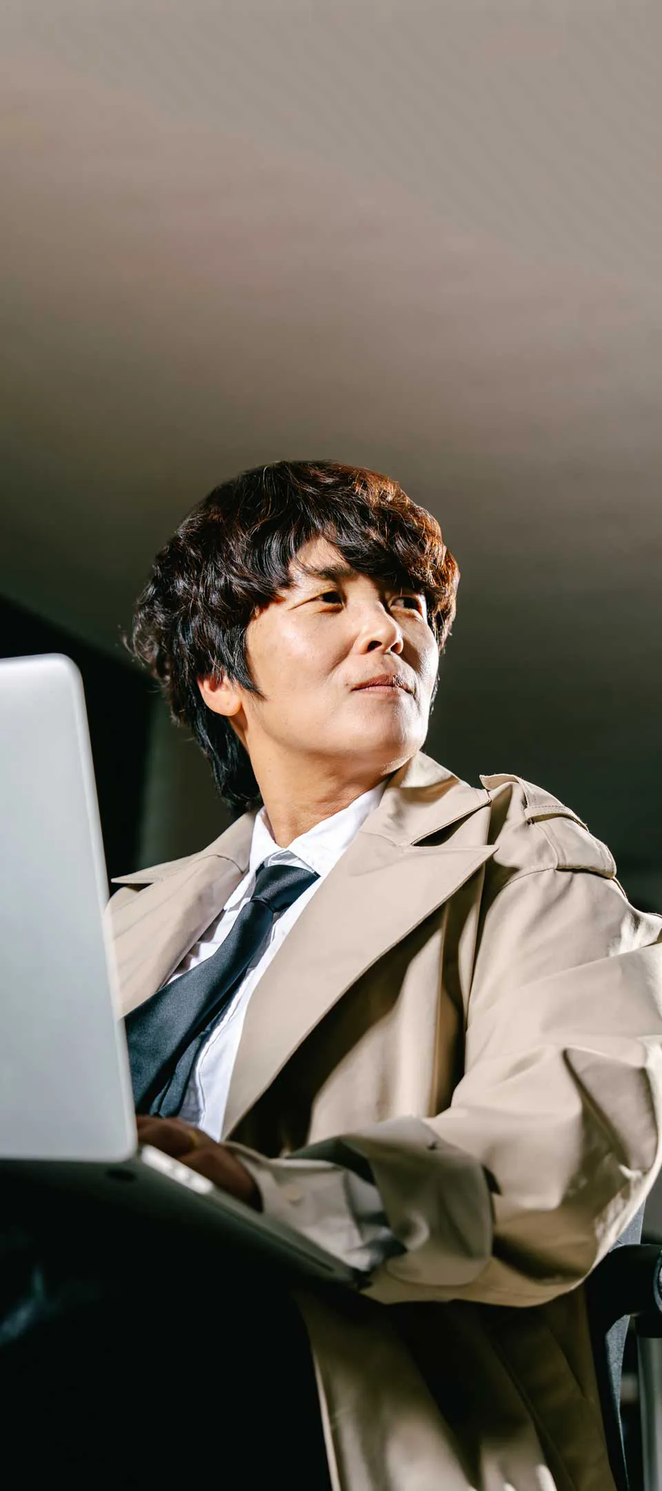 탐정 복장을 입은 김용자 이장이 의자에 앉아 노트북으로 사건 보고서를 찾아보고 있는 것처럼 연출된 사진. 예리한 눈으로 프레임 오른쪽의 어딘가를 응시하고 있다.